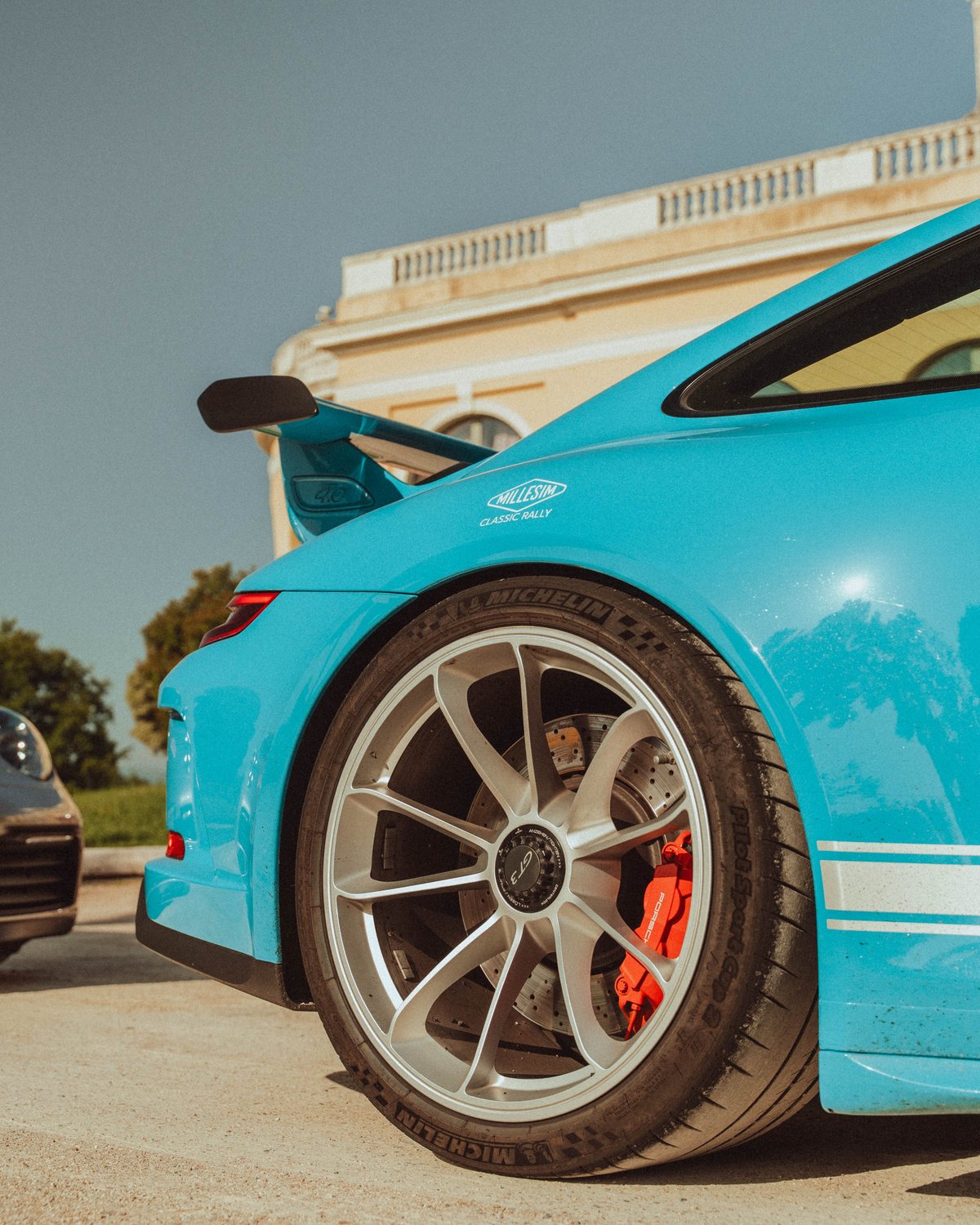 Jante argentée et étrier rouge d'une Porsche 911 GT3 bleue portant le sticker Millesim Classic Rally
